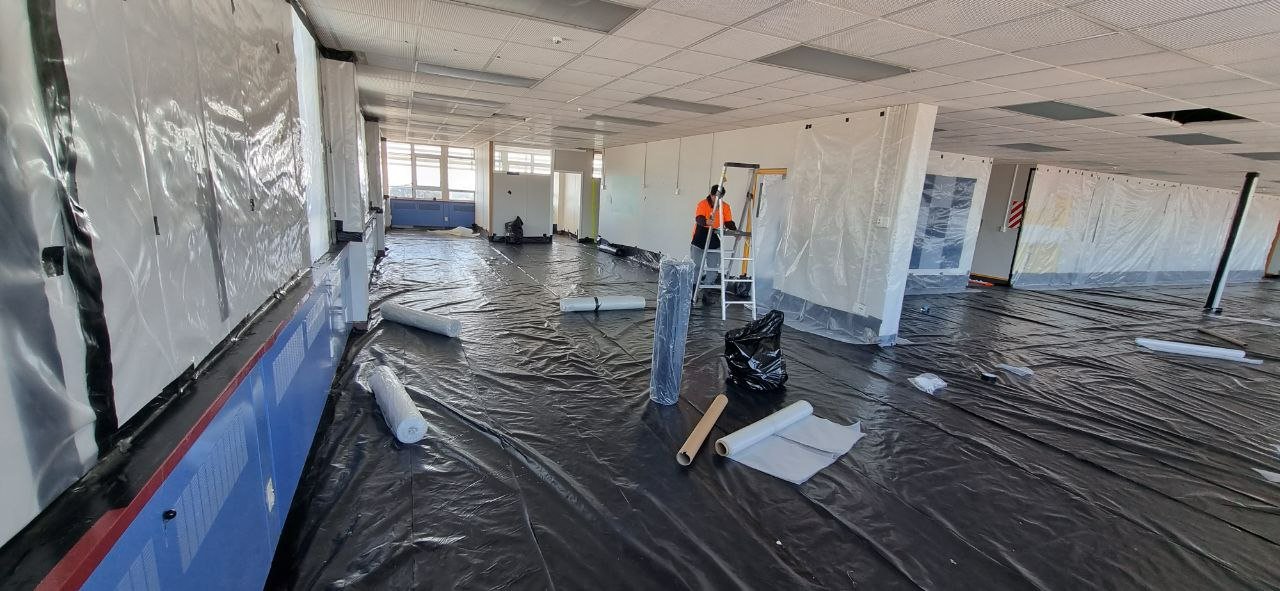 A worker encloses the interior of a building in preparation for asbestos removal. 