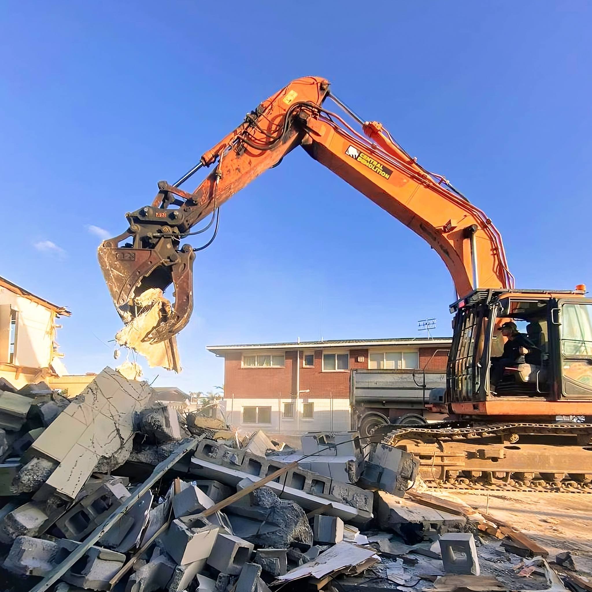 A digger removes part of a wall from a residential demolition project.