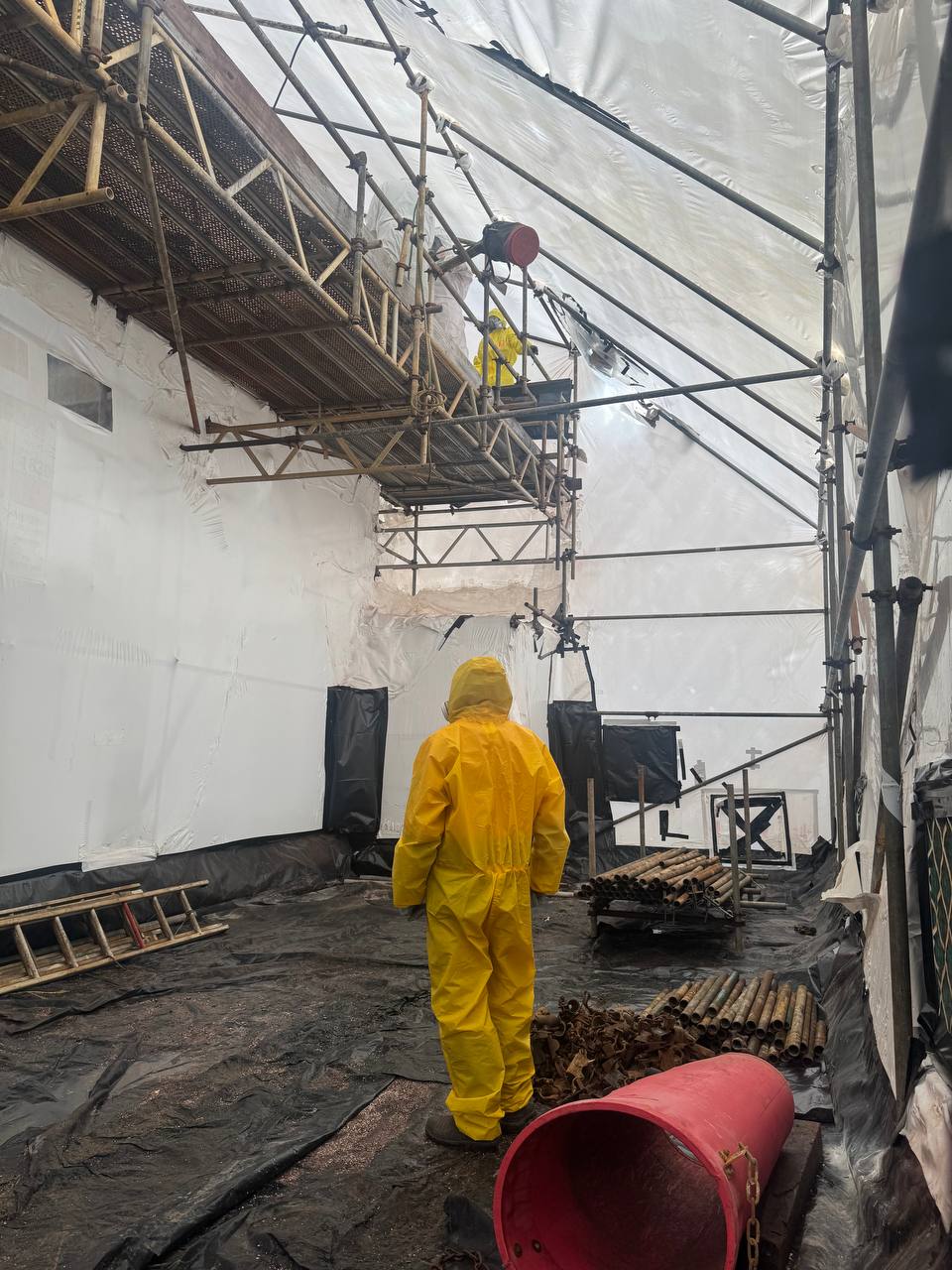 Workers within an asbestos containment enclosure.